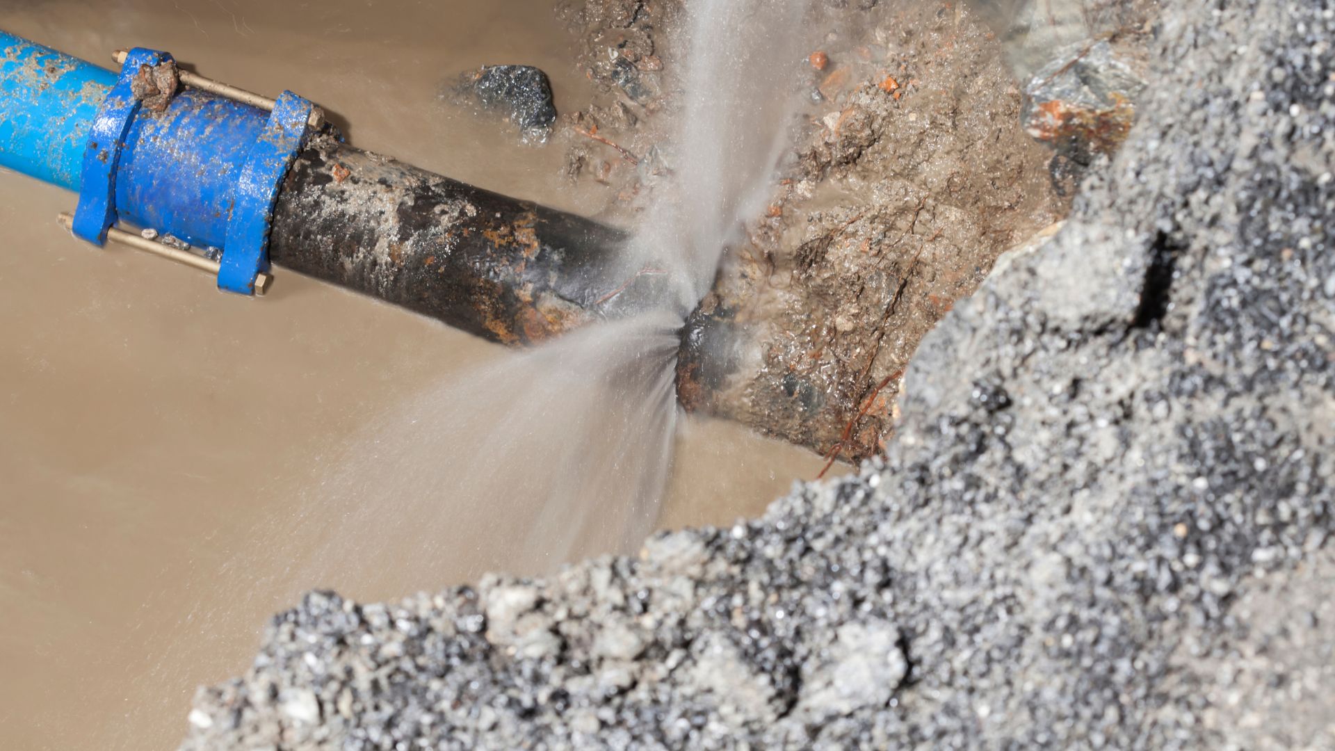 A blue pipe pouring water into a muddy area