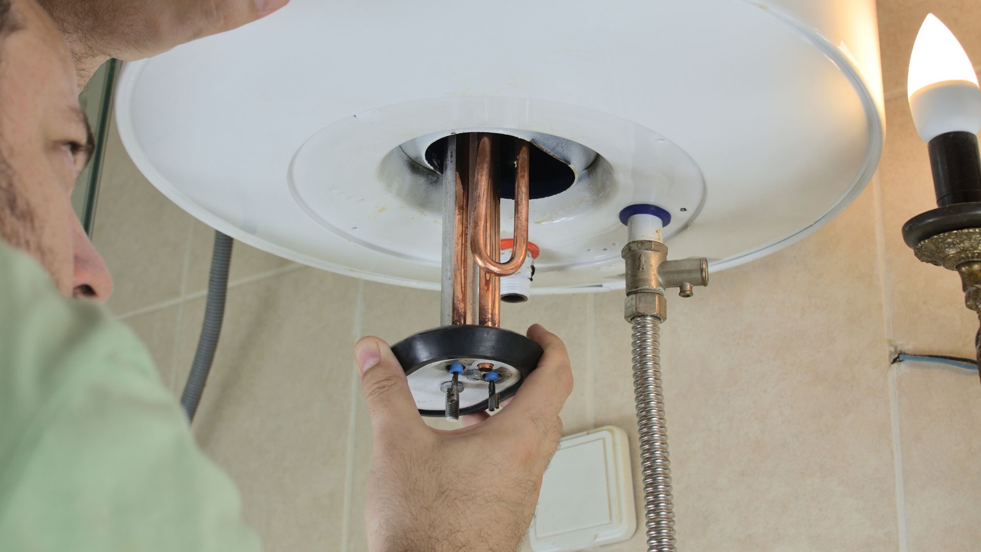 A man working on a ceiling fan in a bathroom