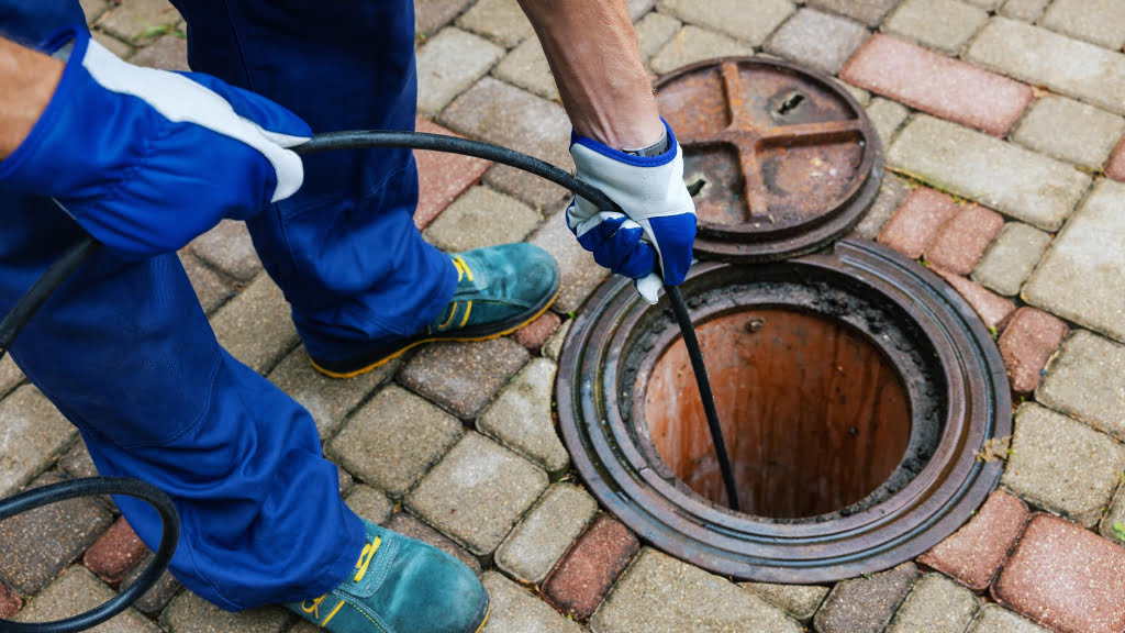 A man is using a hose to clean a manhole